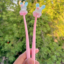 Load image into Gallery viewer, Two Pink Dancing Bunny Gel Pens with Bunny Design Held in a Hand Against a Blurred Green Outdoor Background - Tinyminymo