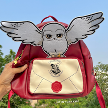 Load image into Gallery viewer, Red Harry Potter's Hedwig Backpack with an Owl Design and Hogwarts Crest, Held by Hand Outdoors - Tinyminymo