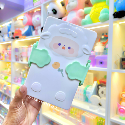 Green Adorable Sheep Snack Box held in front of a Colorful Toy Store Display - Tinyminymo