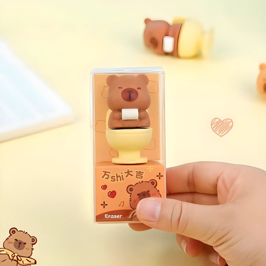 Hand holding a Capybara Eraser with packaging on a light yellow background - Tinyminymo