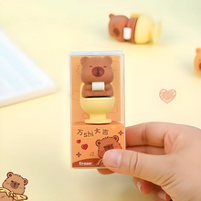 Load image into Gallery viewer, Hand holding a Capybara Eraser with packaging on a light yellow background - Tinyminymo
