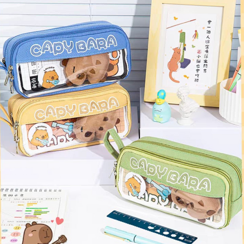 Three 'Capybara' themed pencil cases in different colors kept on a desk with other stationery items - Tinyminymo