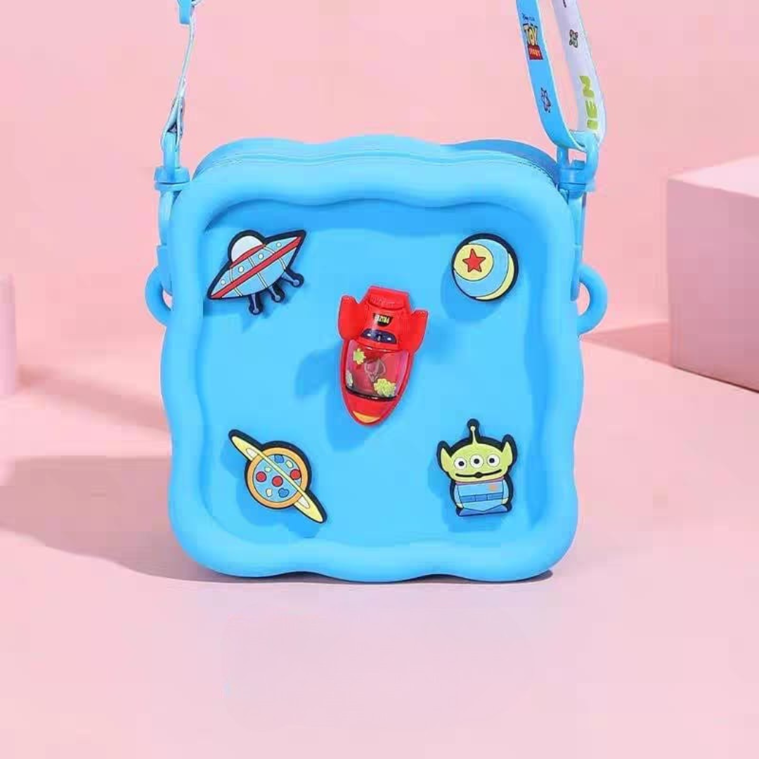 Blue Character Silicone Sling Bag with Colorful Space Themed Patches on a Pink Background - Tinyminymo
