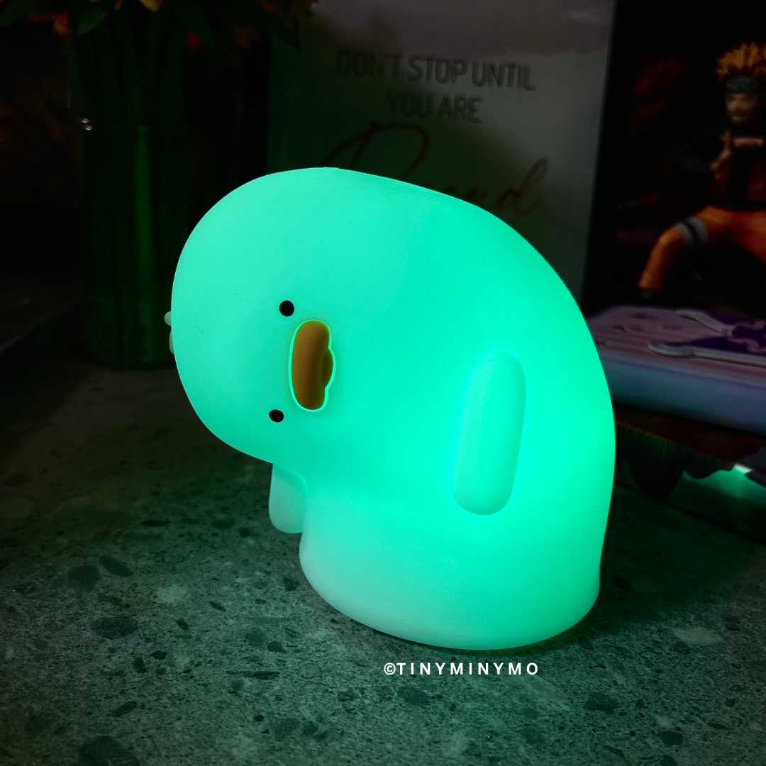 Crooked Neck Duck Silicone Night Light Glowing Green in Dark Background with Naruto Action Figure and Some Books at the Side - Tinyminymo