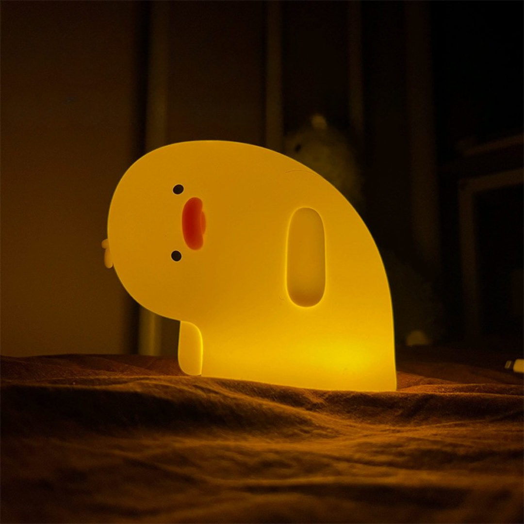 Crooked Neck Duck Silicone Night Light Glowing Yellow in Dark Background, Kept on a Blanket - Tinyminymo
