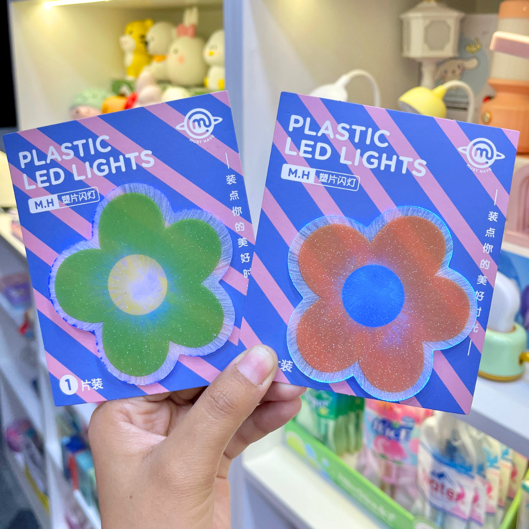 Two Pieces of Cute Flower Stick on Light held in front of a store shelf - Tinyminymo