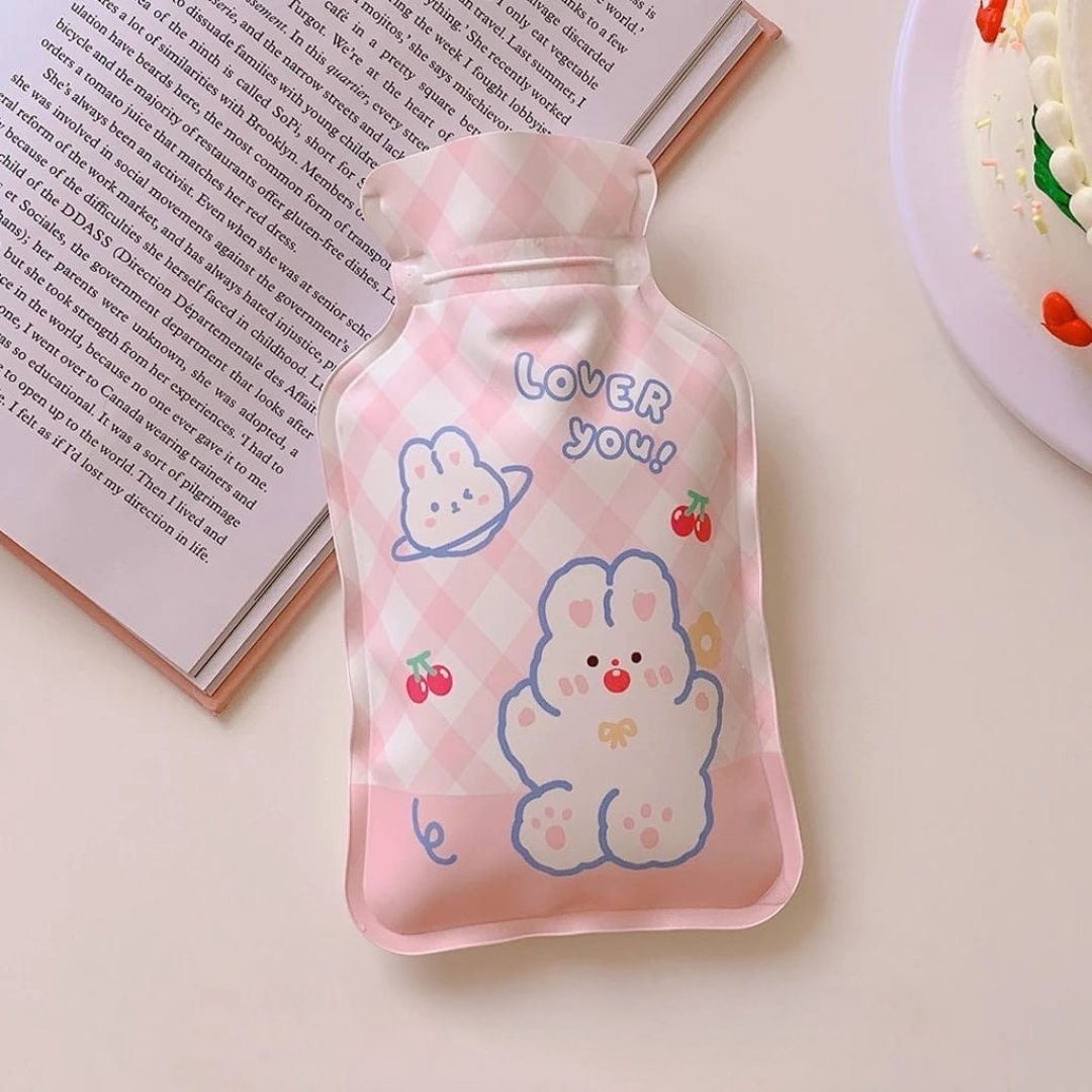 Pink Cute Hot Water Bag with cartoon print  on a light surface against to an open book - Tinyminymo