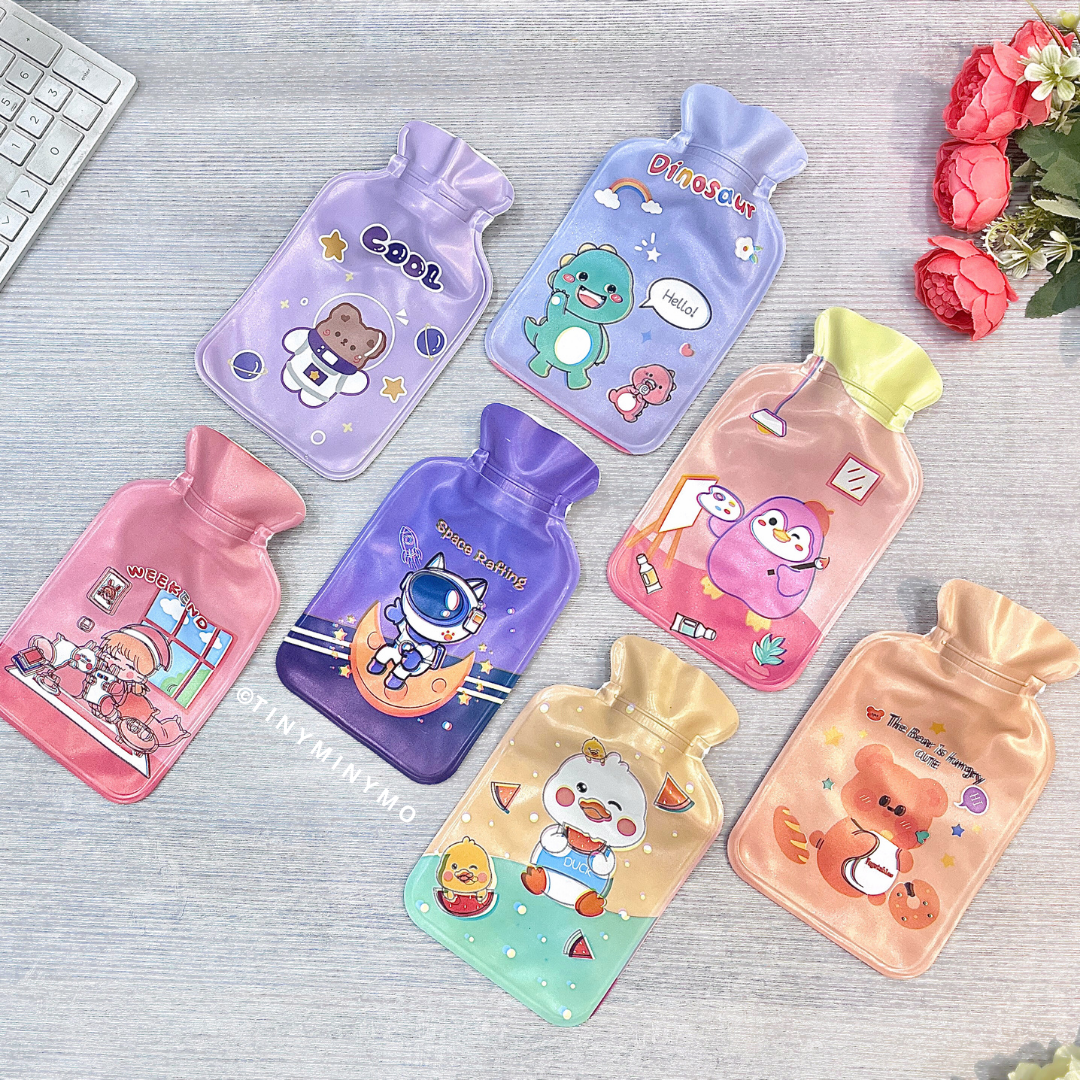 A vibrant set of cartoon-themed Cute Hot Water Bags arranged on a light grey surface, with flowers and a Keyboard in the Background - Tinyminymo