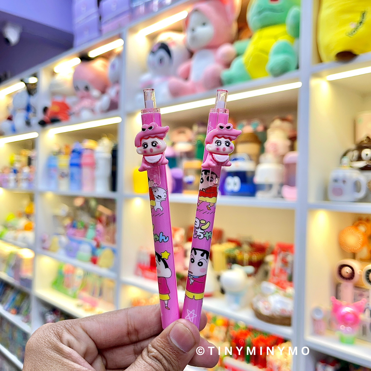Two Pink Shin-chan Pens held in Front of a Colorful Display - Tinyminymo