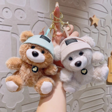 Load image into Gallery viewer, Two Cute Teddy Plush Keychain with hats held by a hand against a decorative wall - Tinyminymo
