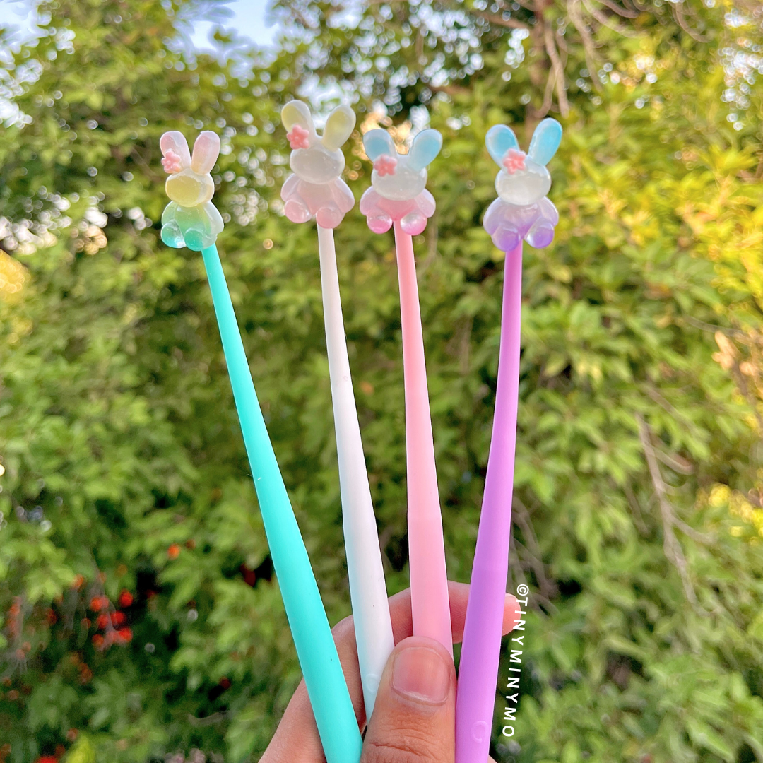 Set of Four Colorful Dancing Bunny Gel Pens with Cute Bunny Designs Held Against a Green Outdoor Background - Tinyminymo