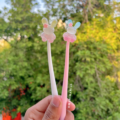Two Dancing Bunny Gel Pen Held by a Hand Against a Blurred Green Outdoor Background - Tinyminymo
