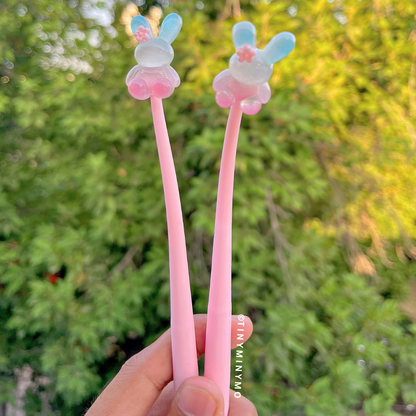 Two Pink Dancing Bunny Gel Pens with Bunny Design Held in a Hand Against a Blurred Green Outdoor Background - Tinyminymo