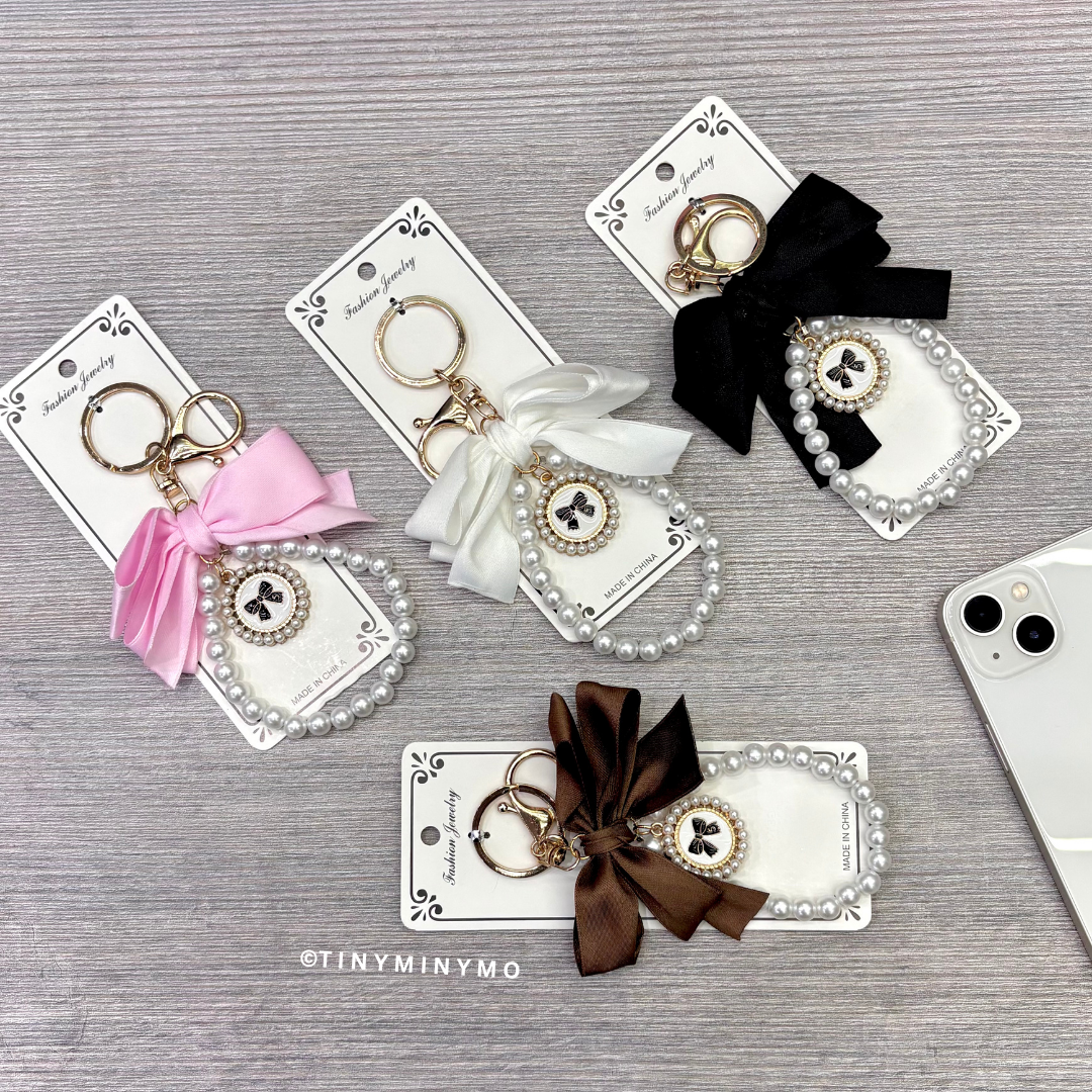 Black, Pink, White and Brown Bow Mobile Charm on a Wooden Surface - Tinyminymo