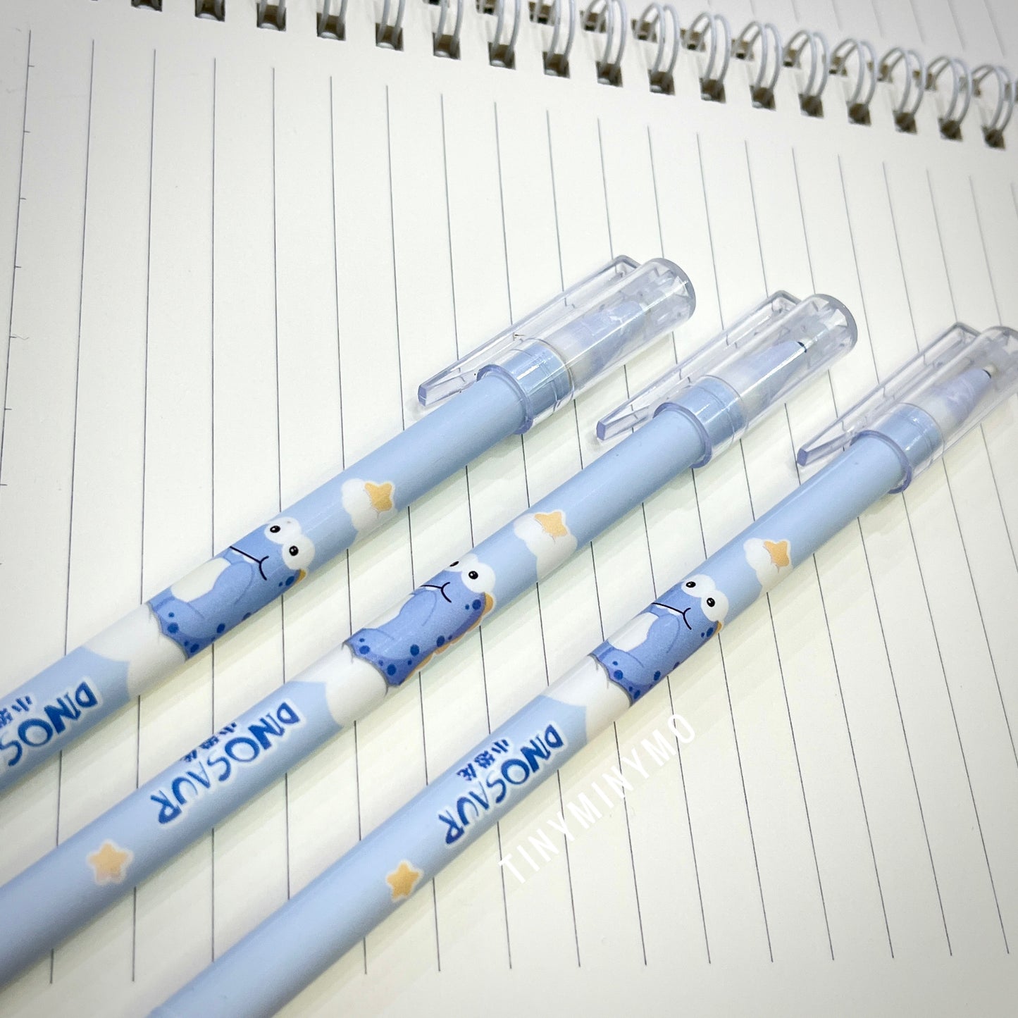 Three Blue Pens with Dinosaur Characters on a lined notebook page - Tinyminymo