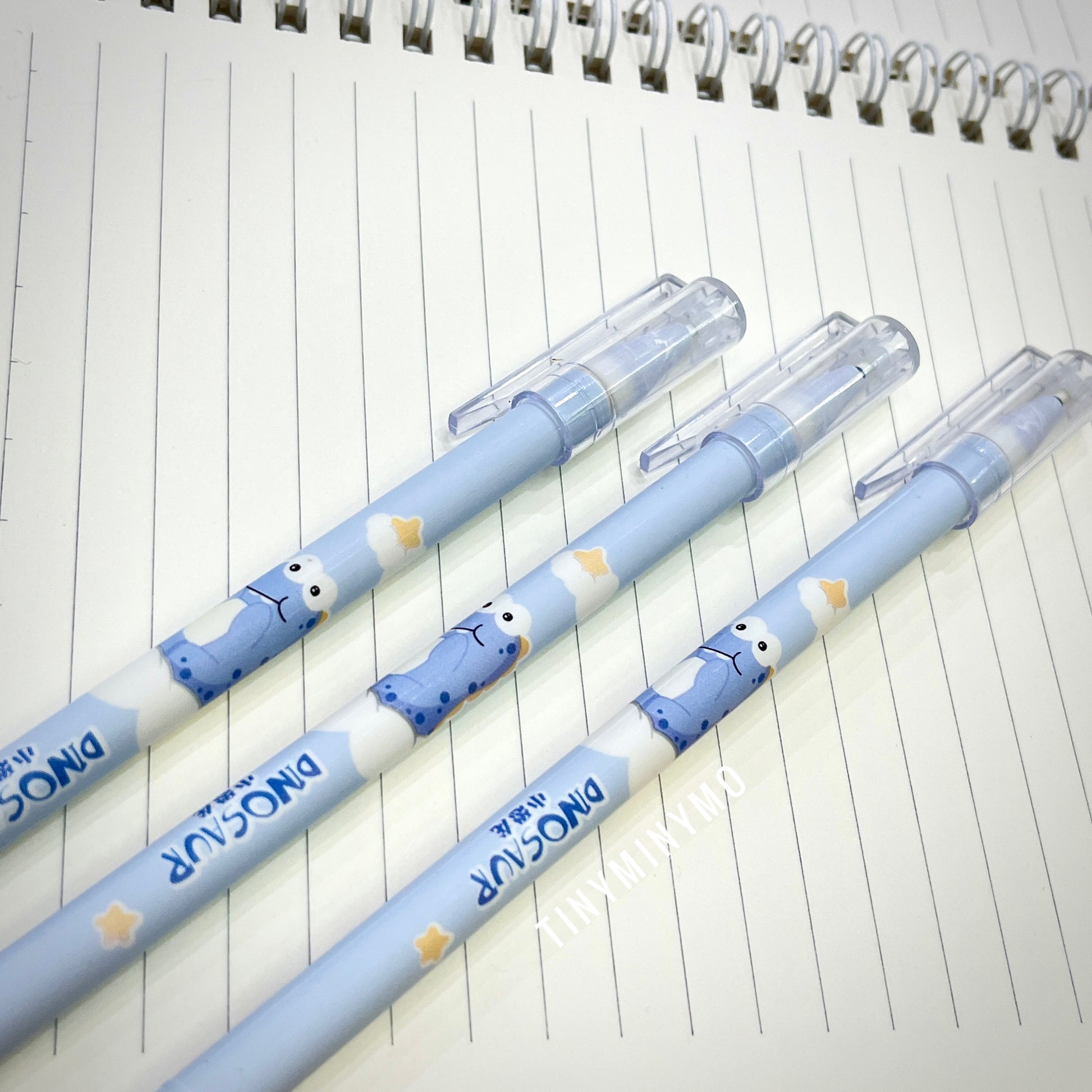 Three Blue Pens with Dinosaur Characters on a lined notebook page - Tinyminymo