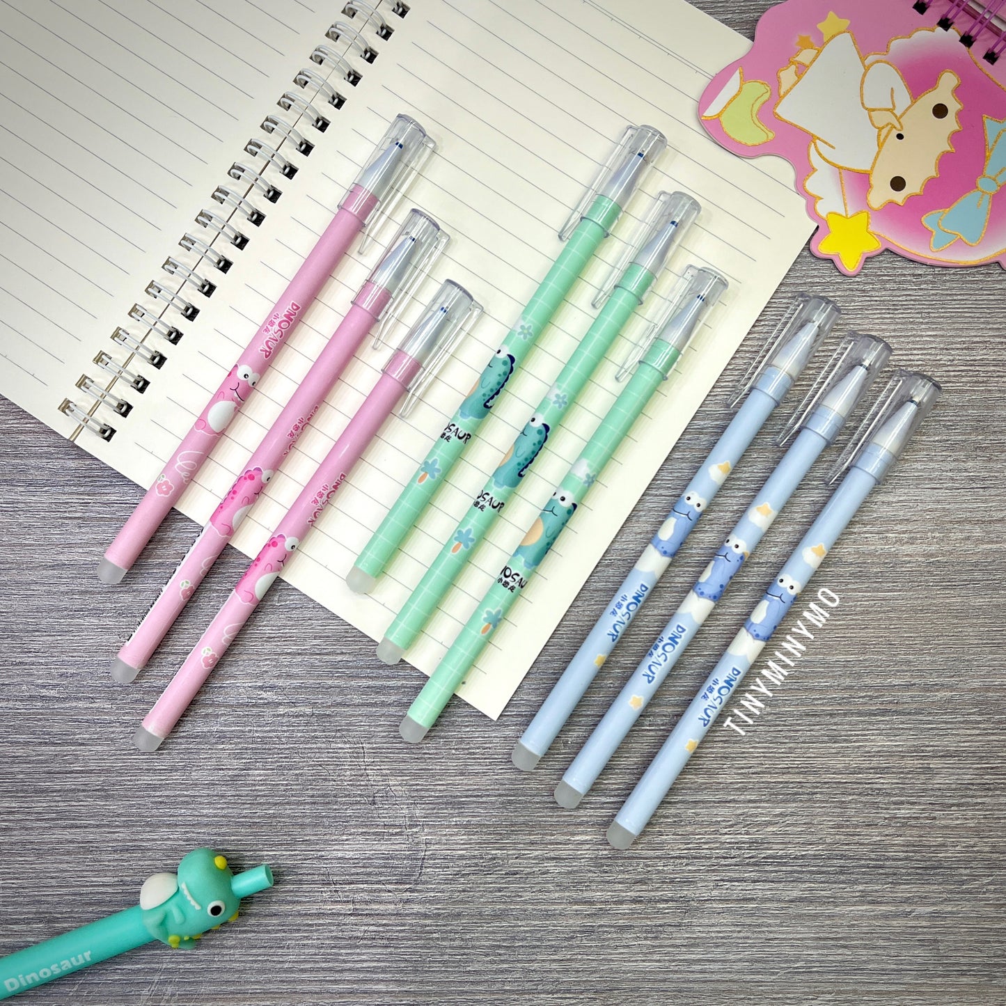 Set of Colorful Erasable Dinosaur Gel Pens on a Wooden Surface with a Notebook - Tinyminymo