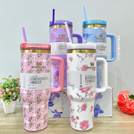Four Colourful Floral Stanley Cups with Handles on a Wooden Surface - Tinyminymo
