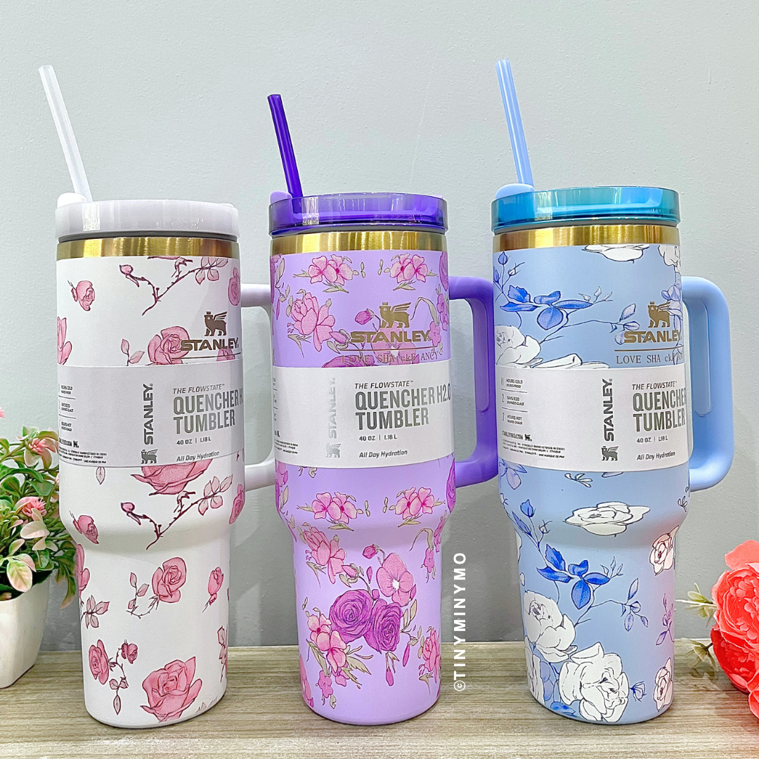 Three Colourful Floral Stanley Cups with Handles and Straws on a Wooden Surface - Tinyminymo
