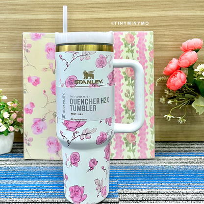 White Floral Stanley Cup on a Textured Blue Surface with Flowers in the Background - Tinyminymo