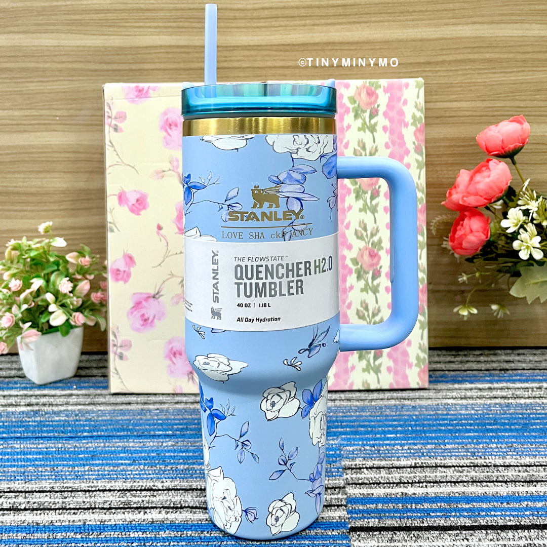 Blue Floral Stanley Cup with a Straw on a Blue Textured Surface with Flowers in the Background - Tinyminymo