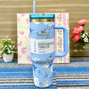 Blue Floral Stanley Cup with a Straw on a Blue Textured Surface with Flowers in the Background - Tinyminymo