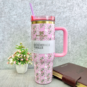 Pink Floral Stanley Cup with a Handle on a Grey Surface with a Plant and Diary in the Background - Tinyminymo