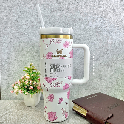White Floral Stanley Cup with a Floral Design on a Grey Textured Surface with a Plant and Diary in the Background - Tinyminymo