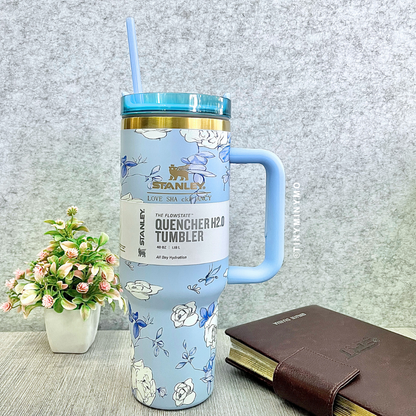 Blue Floral Stanley Cup with a Handle on a Grey Textured Surface, with a Plant and Book in the Background - Tinyminymo