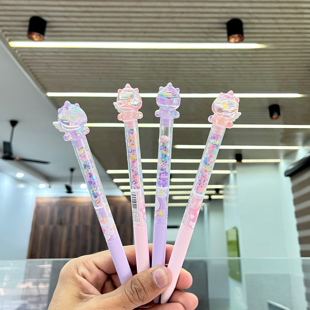 Four Glitter Unicorn Pen Held in a Hand, blurred indoor background - Tinyminymo