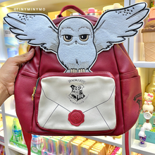 Load image into Gallery viewer, Red Harry Potter's Hedwig Backpack with Owl Design and 'Hogwarts' Emblem Held in Front of a Store Shelf - Tinyminymo

