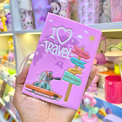 Pink Kawaii Passport Cover Featuring a Car and City Names Illustration, Held in Hand Against a Colorful Background - Tinyminymo