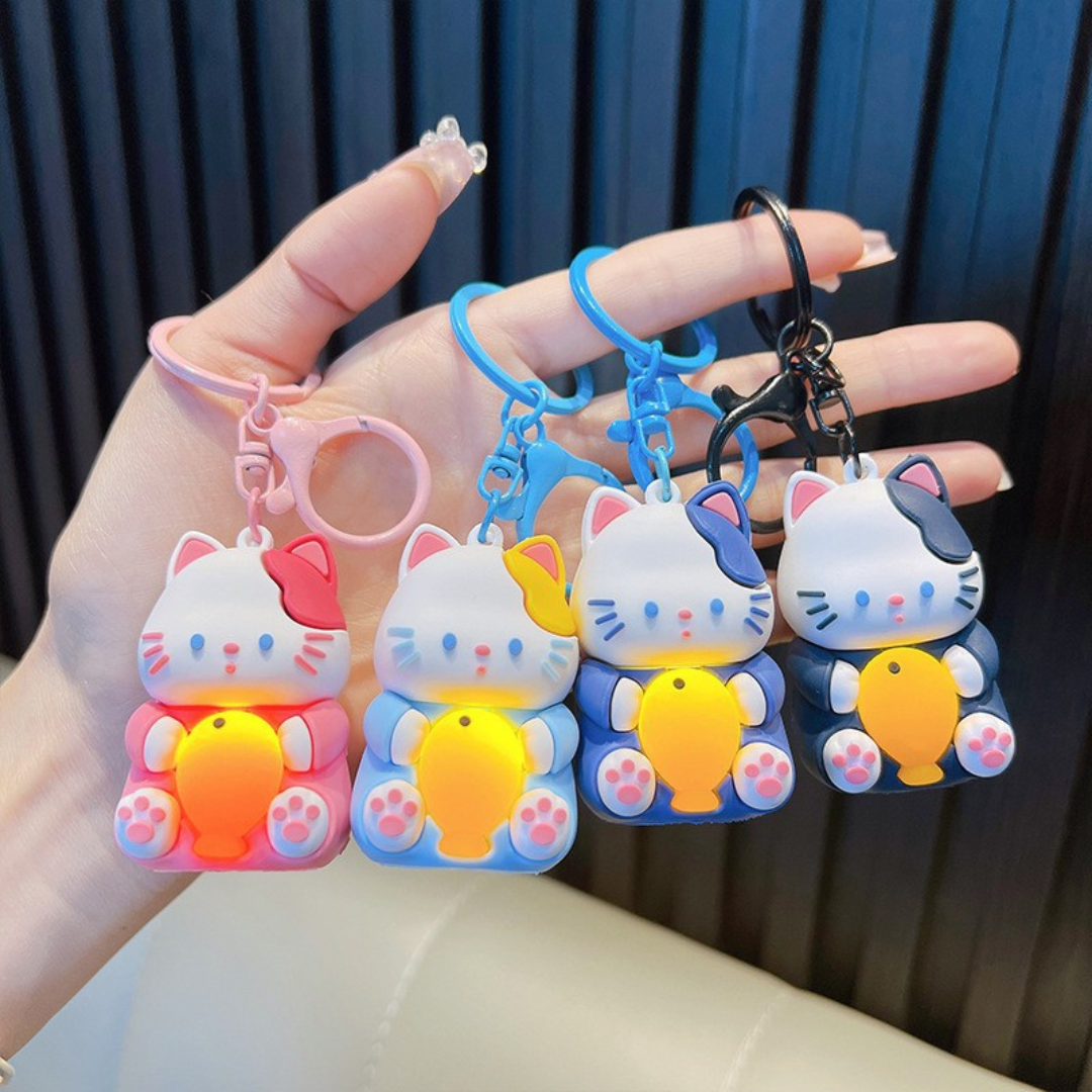 A Hand Holding Four Different Colored Light-Up Cat Keychains with a Yellow Fish  - Tinyminymo