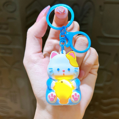 A Hand Holding a Sky Blue Lightup Cat Keychain with Yellow Fish - Tinyminymo