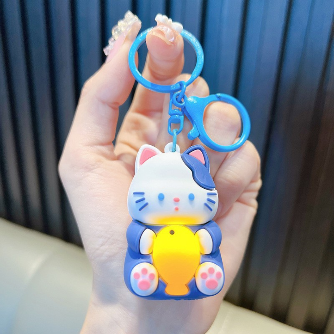 A Hand Holding a Blue Lightup Cat Keychain with a Yellow Fish - Tinyminymo