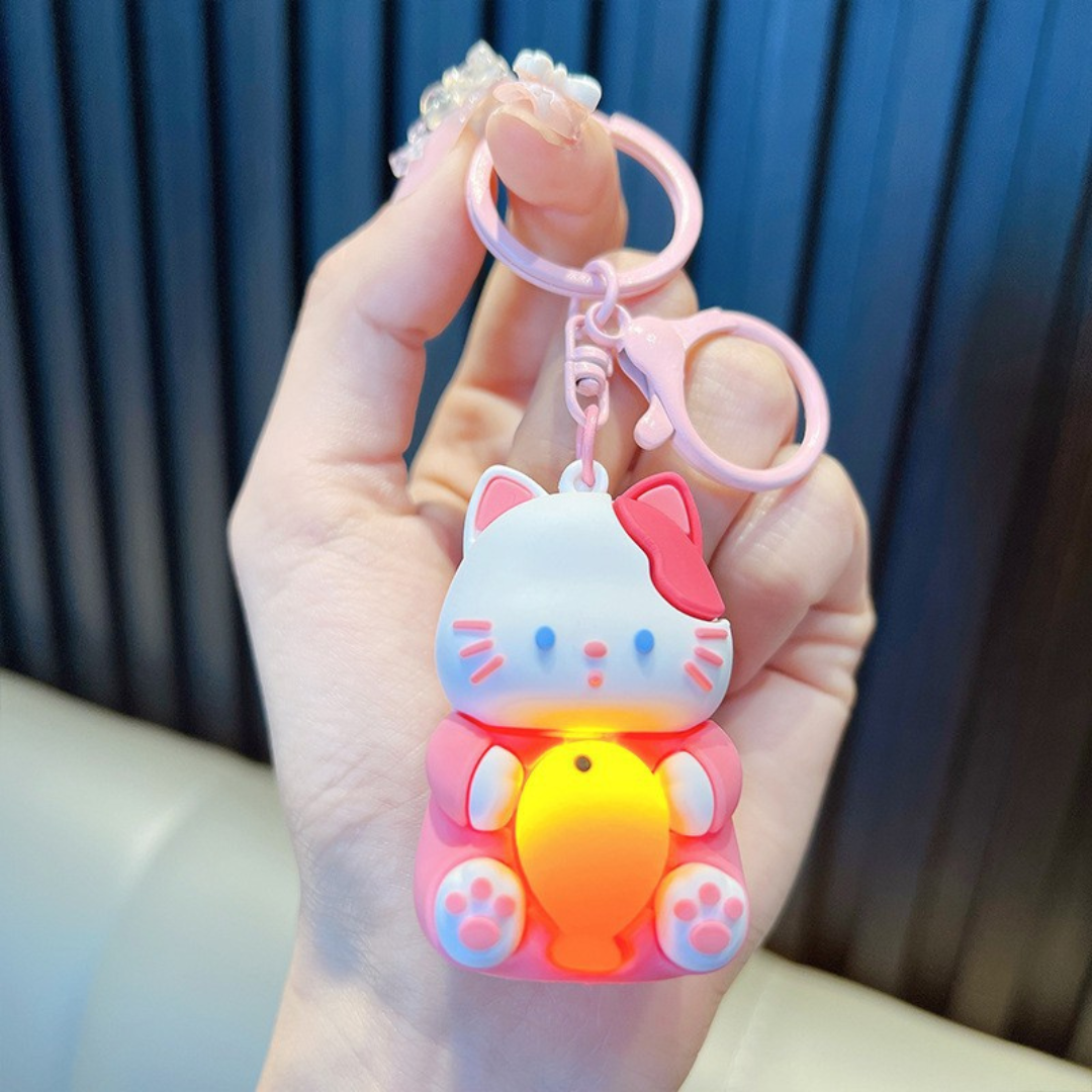 A Hand Holding a Pink Lightup Cat Keychain with a Yellow Fish - Tinyminymo