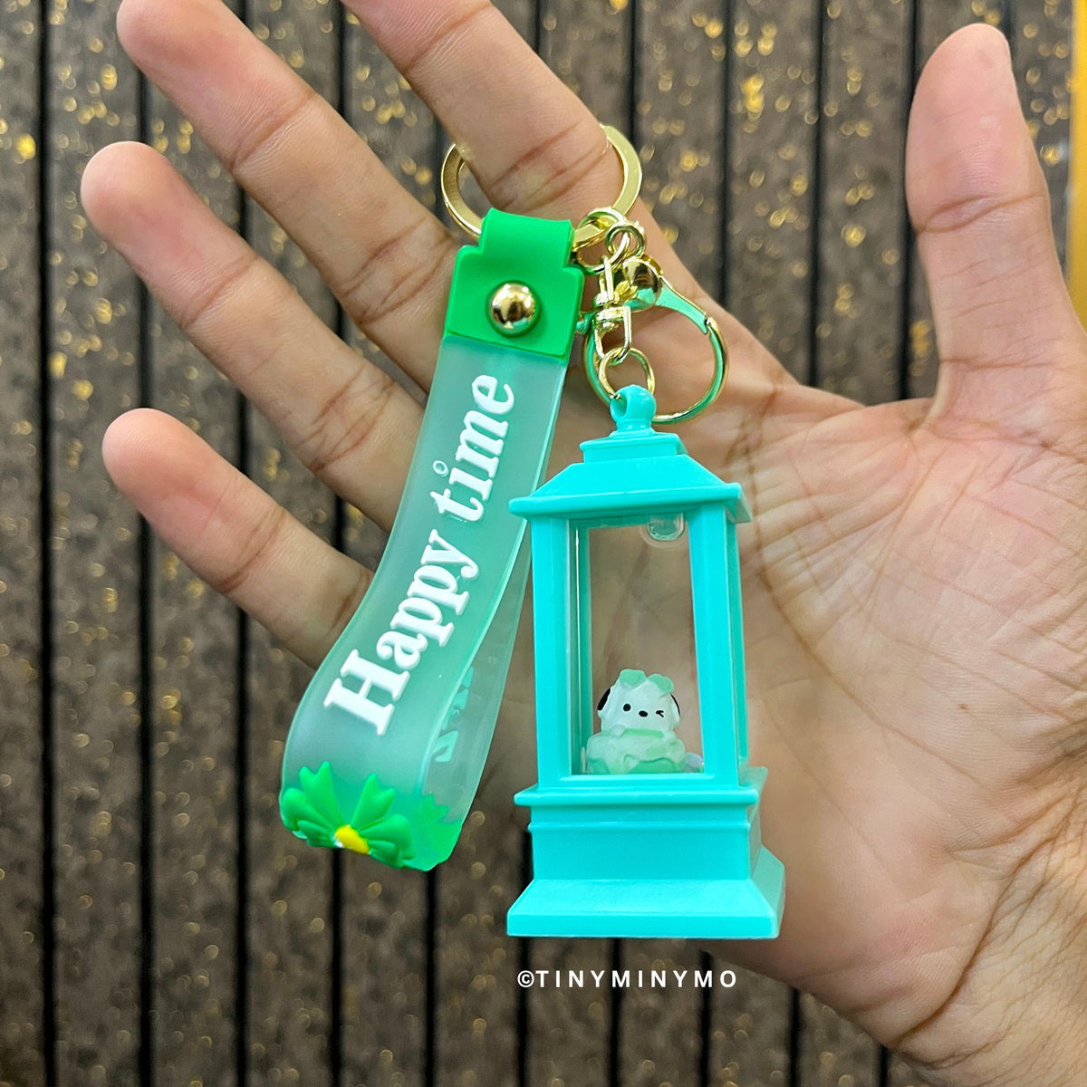Lightup Keychain with 'Happy Time' Tag Held in a Hand Against a Wooden Background - Tinyminymo