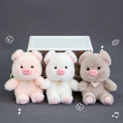 Three Plush Piggy 3D Keychains in Pink, White, and Greige Sitting in Front of a Box on a Dark Background with Playful Doodles - Tinyminymo