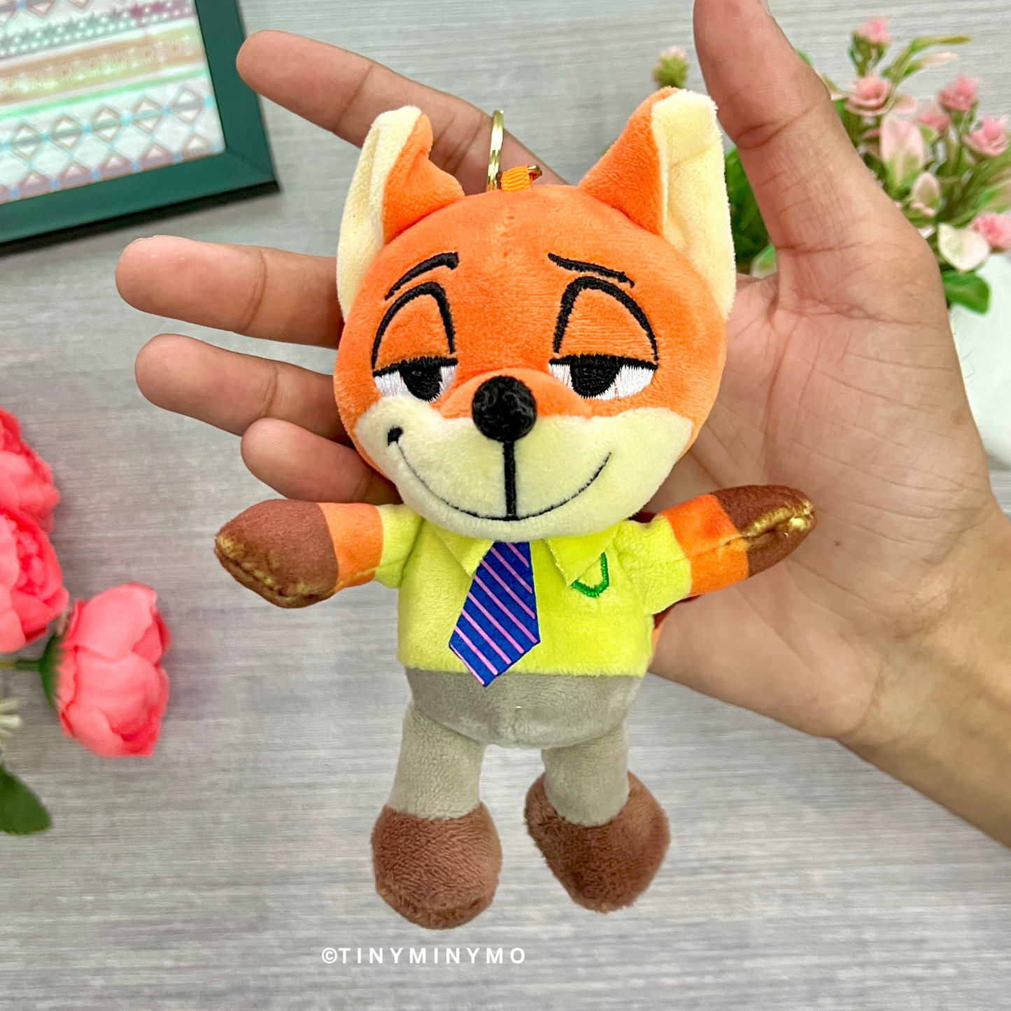 Plush Zootopia 3D Keychain Held in a Hand with Flowers in the Background - Tinyminymo