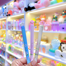 Load image into Gallery viewer, Three Sakura Gel Pen held in front of a store shelf with toys and stationery - Tinyminymo
