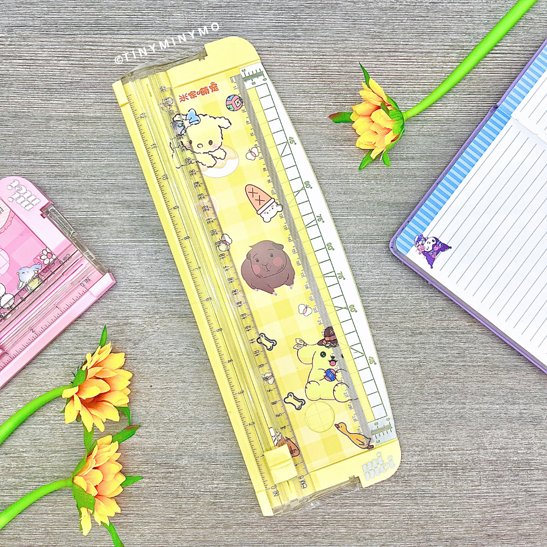 Yellow Paper Trimmer on a Grey Surface with Stationery Items around - Tinyminymo