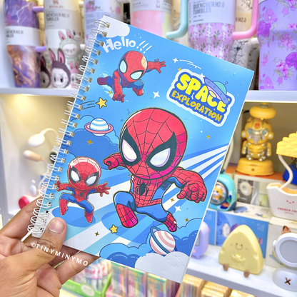 A Spiderman Notebook held up in front of a store shelf filled with various items - Tinyminymo