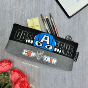 Superhero Pencil Pouch with Various Designs and Text, Placed on a Grey Surface with Flowers and a Notebook - TInyminymo